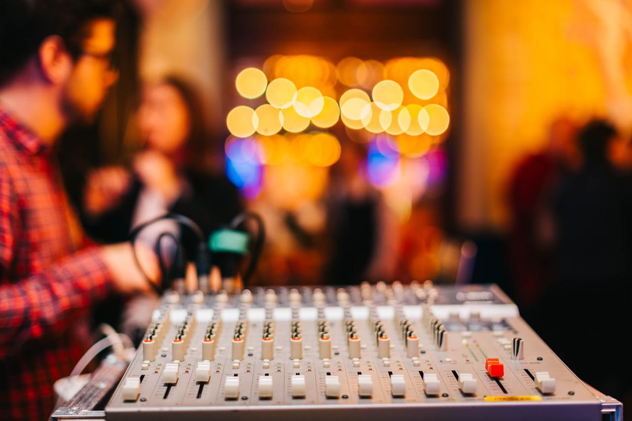Close-up of audio mixer with blurred background at a lively indoor event.