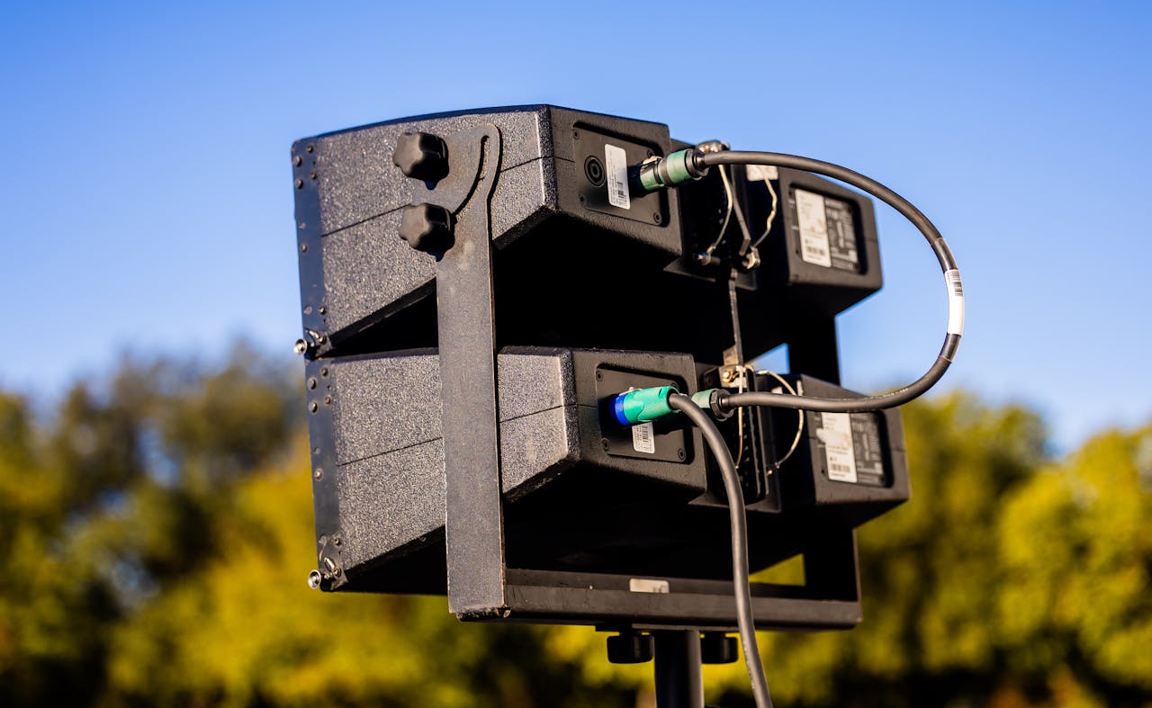 High-quality outdoor speaker setup ready for a live event against a vibrant blue sky.