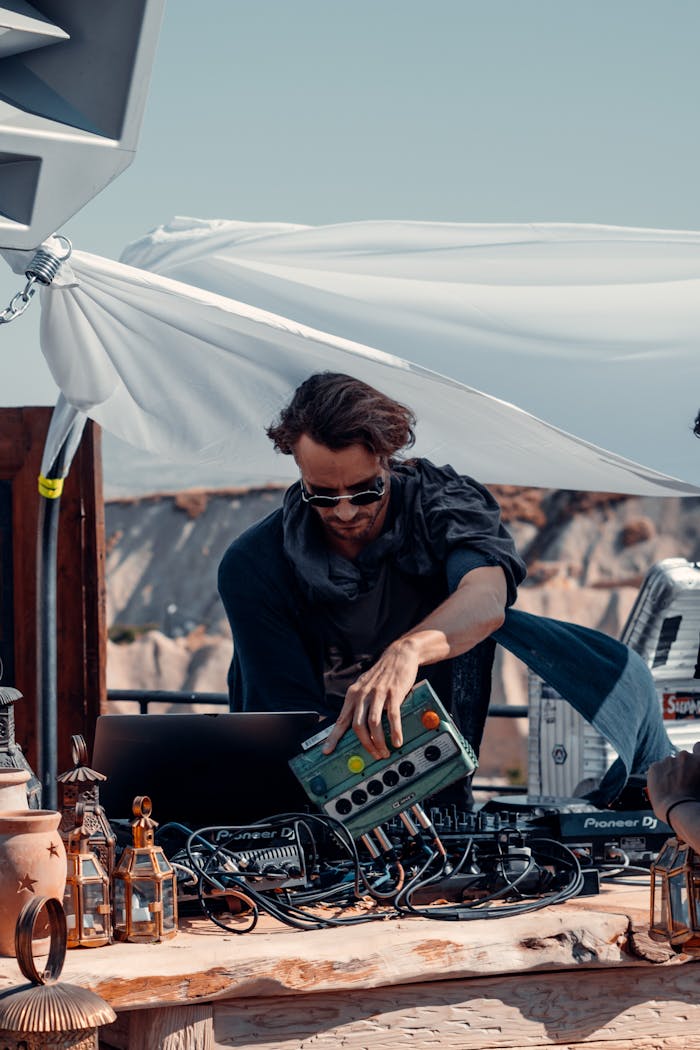 A DJ playing electronic music at an outdoor event in Türkiye with scenic backdrop.